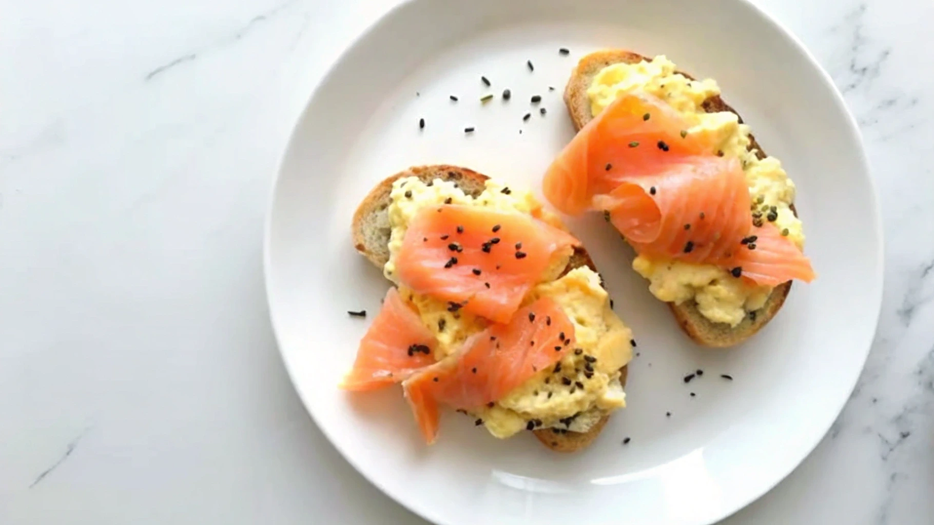 Delicious salmon breakfast with scrambled eggs, avocado, and toast.